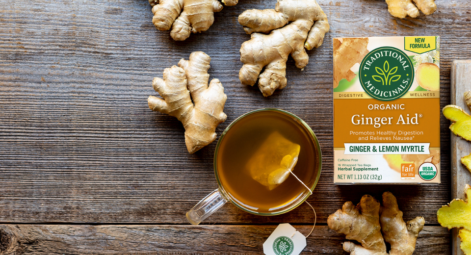 overhead photo of Ginger Aid tea box on table with ginger and cup of tea
